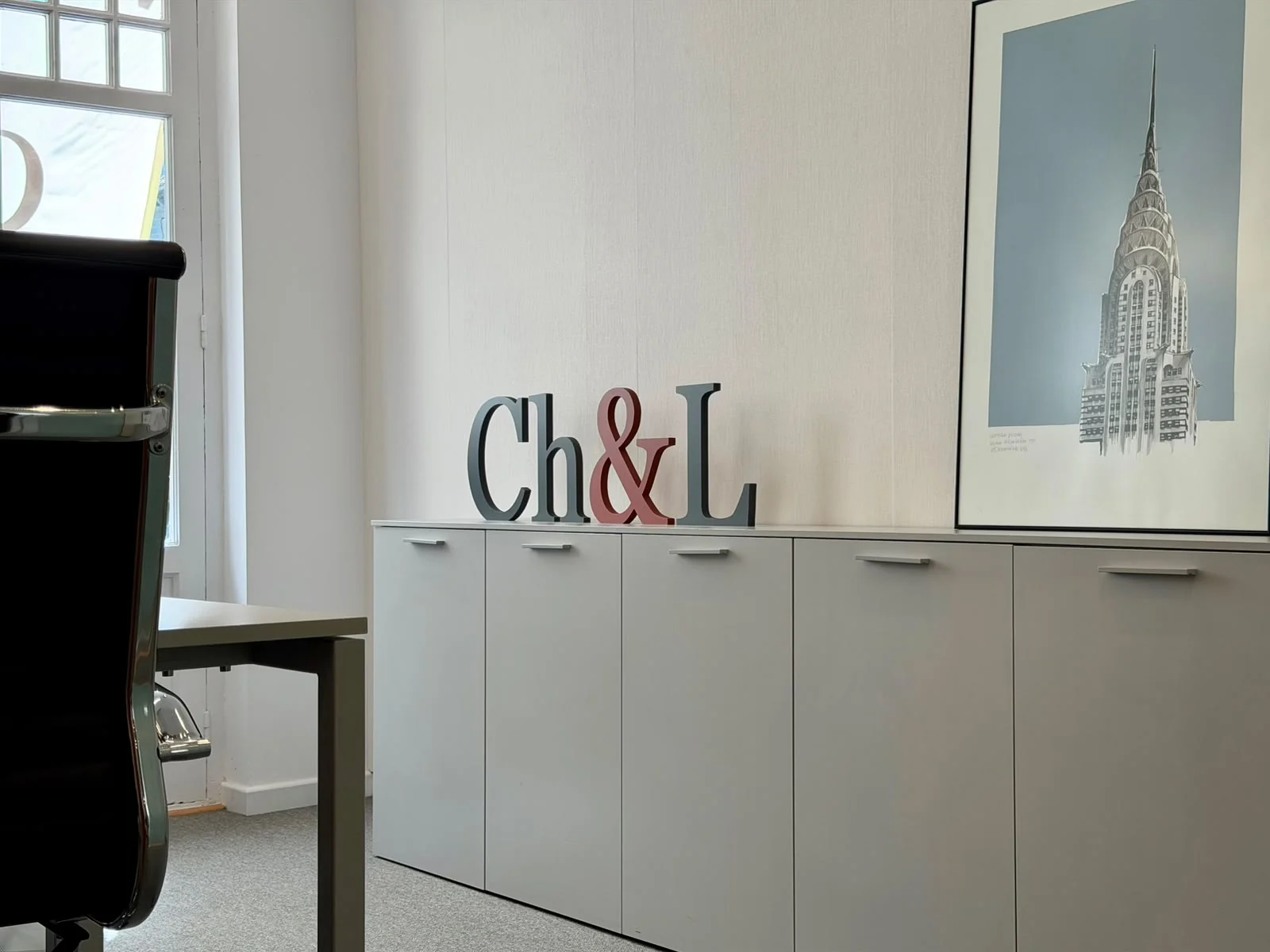 Letras corpóreas con las iniciales Ch&L sobre un mueble del despacho.